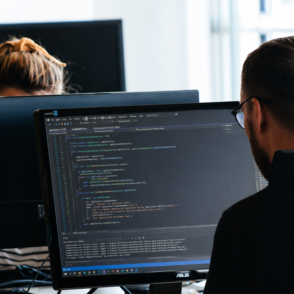 Software developer writing code on a desktop computer in a dark workspace