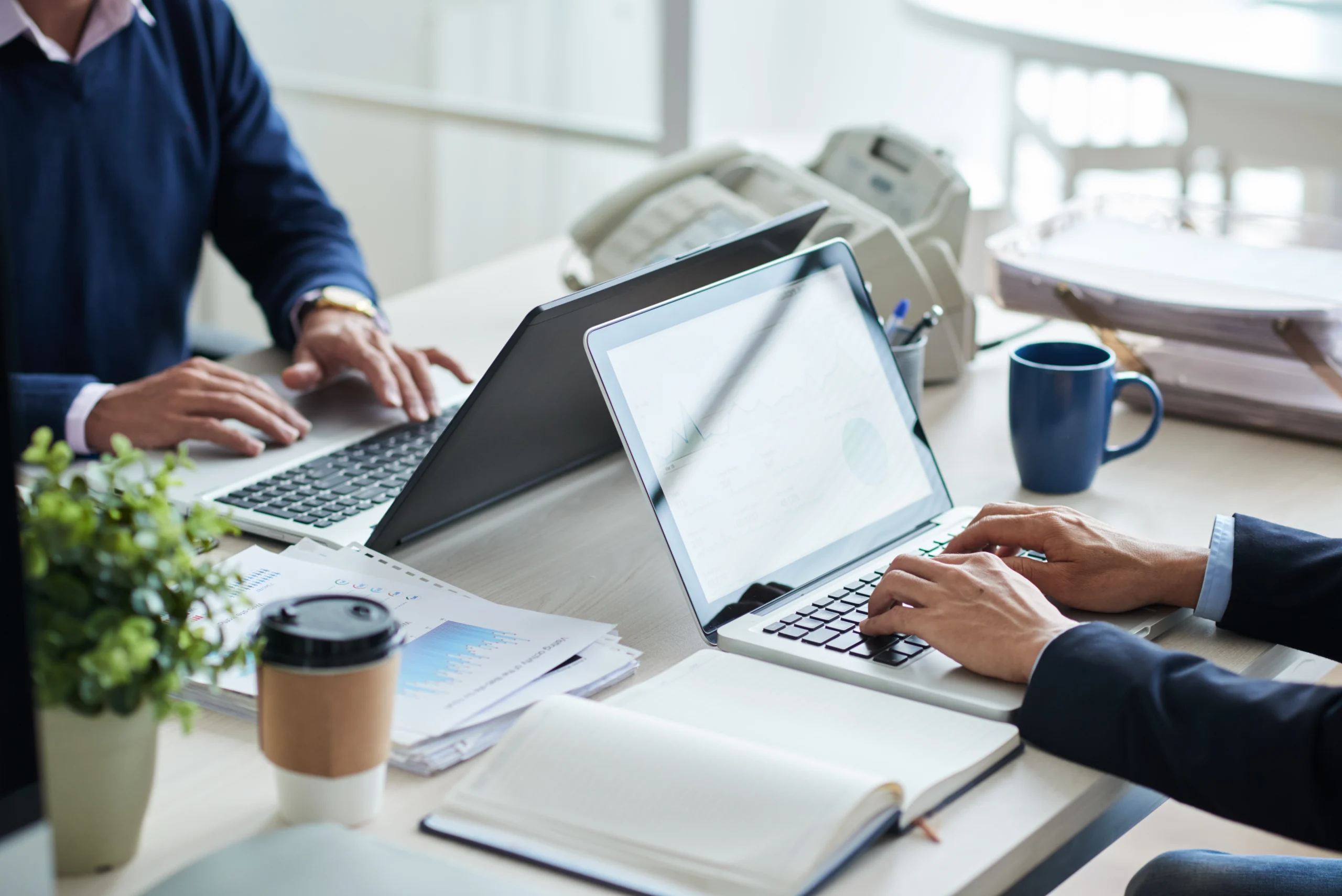 Professionals working together at a desk with laptops and paperwork
