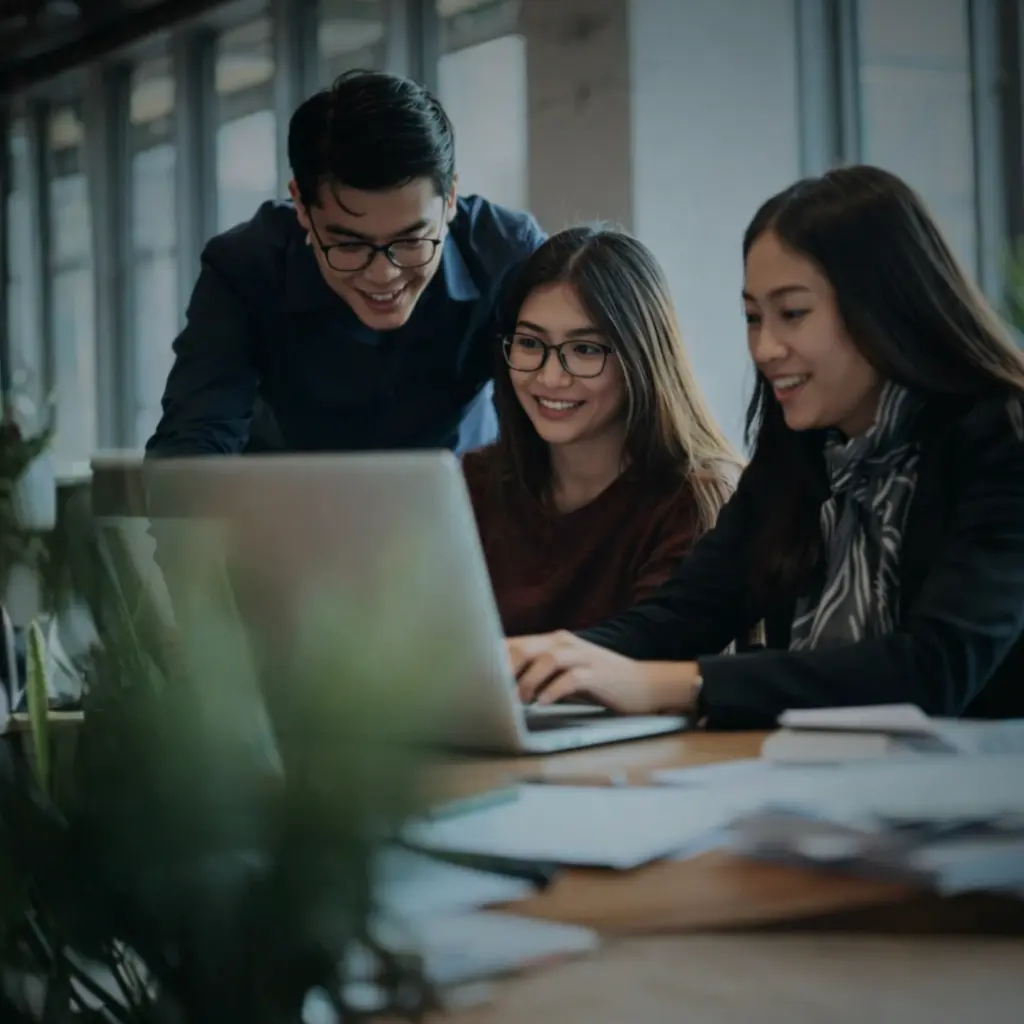 Team members collaborating around a laptop during a hiring and scaling discussion